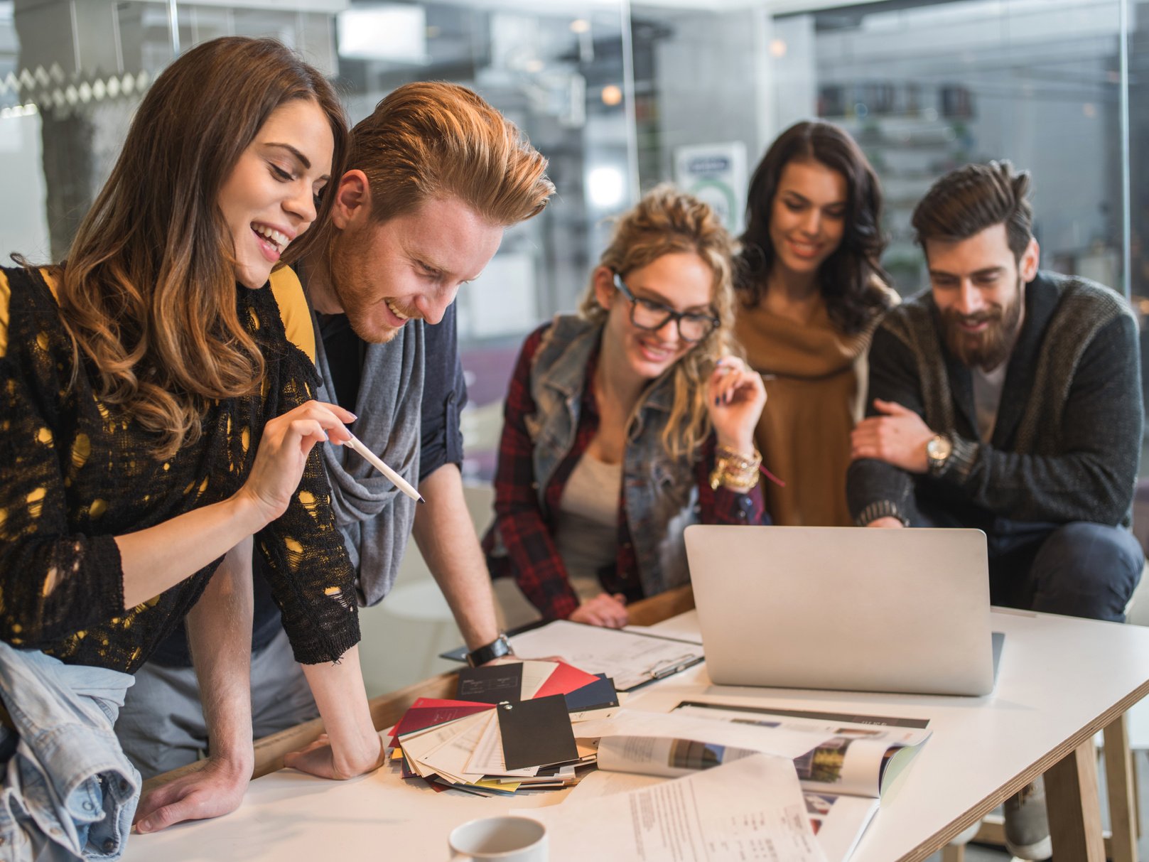 Young fashionable men and women working around a laptop